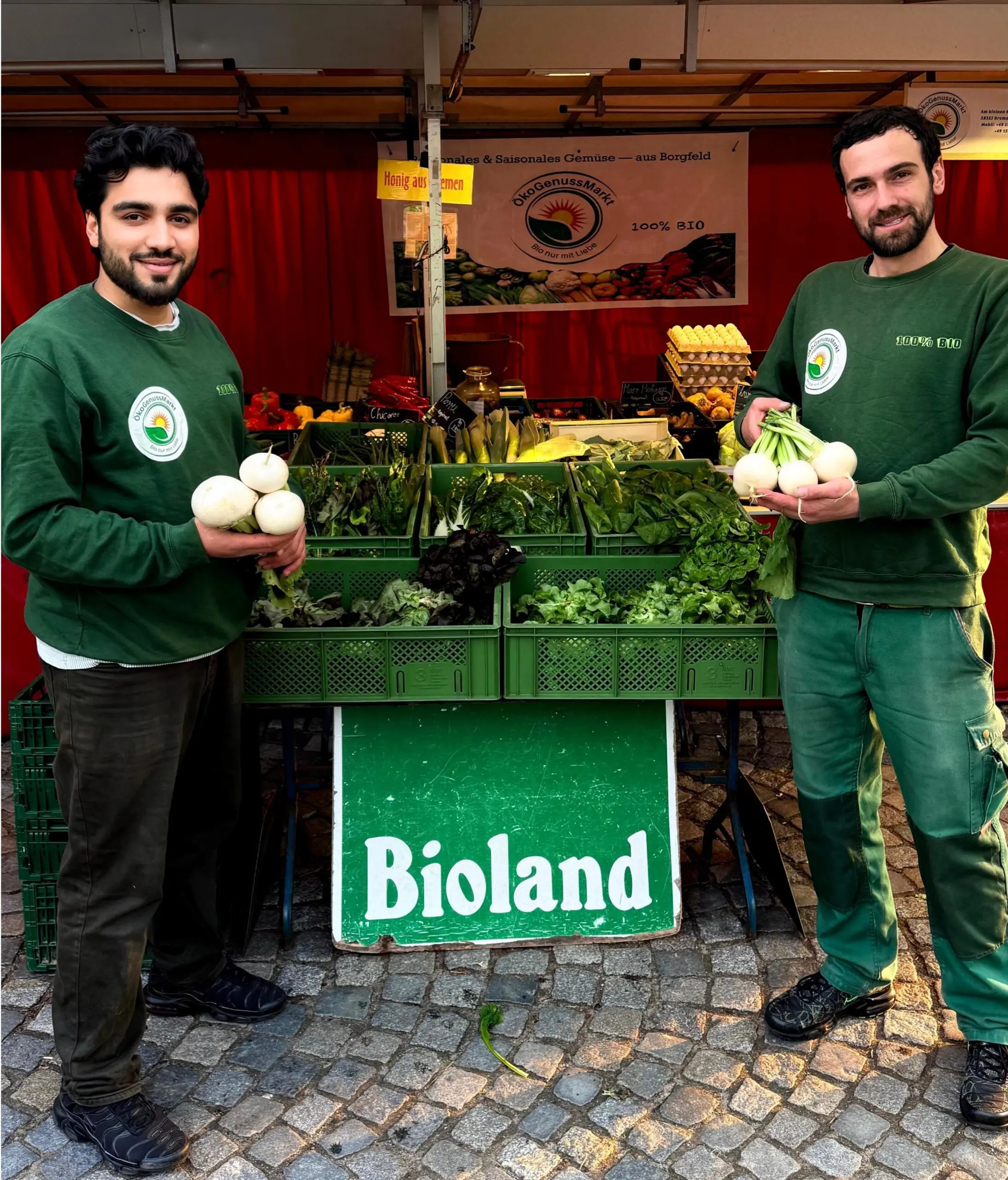 Zwei Männer stehen mit Mairübchen vor einem Marktstand