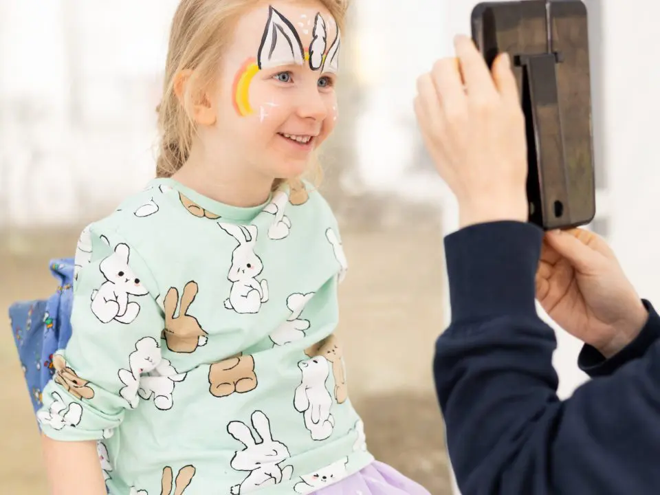 Kind betrachtet sein geschminktes Gesicht im Spiegel