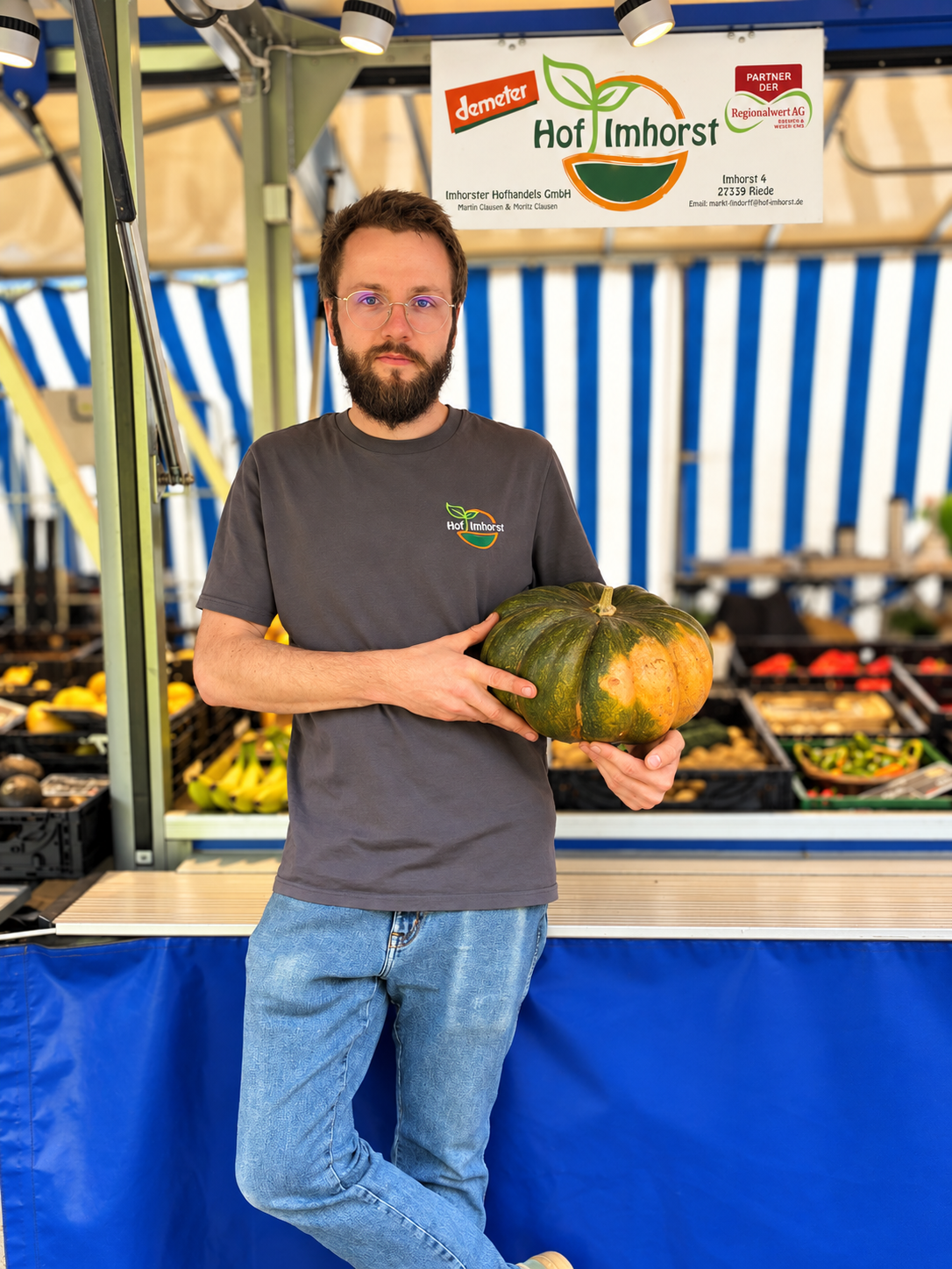 Moritz Clausen steht vor seinem Marktstand mit einem Kürbis in der Hand