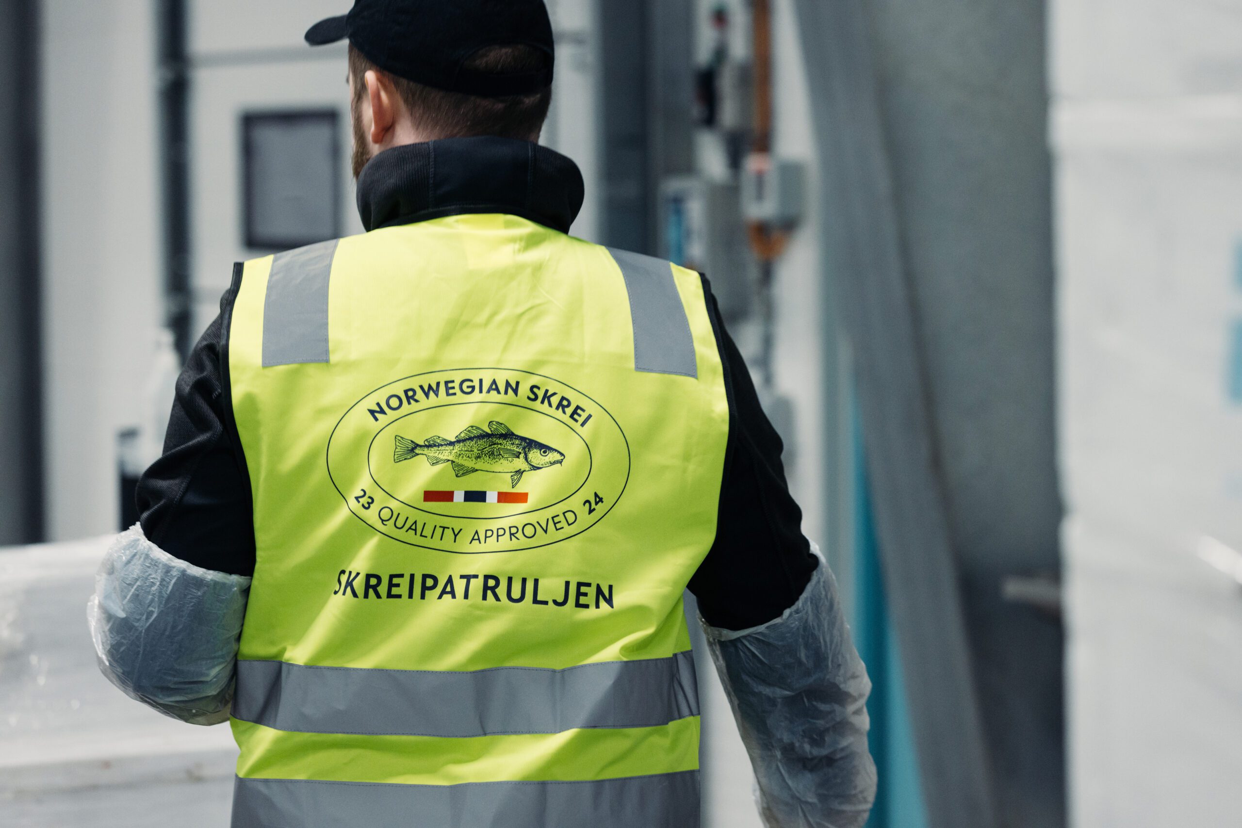Ein Mann mit einer gelben Weste, auf der Skrei-Patruljen steht