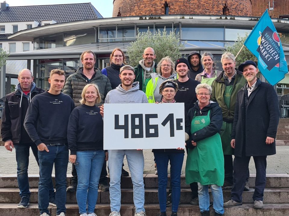 Gruppenbild der Marktbeschicker Geestemünde zum Sozialen Markttag mit Schild nebst Spendensumme.